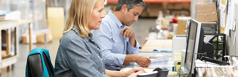 Male and female entrepreneur sitting at work station comparing specs and writing code as part of their mobile app development business.