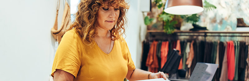 Female entrepreneur working in a home office sitting at a table working on a business plan to turn her home into an Airbnb.