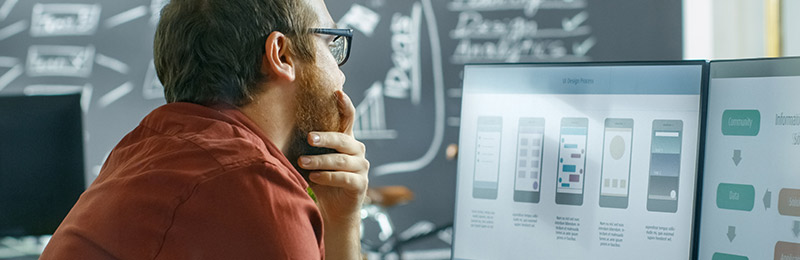 Male entrepreneur sitting in an office in front of computer. Reviewing a research study covering the impact of small business success due to planning.