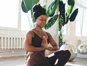 Female african american entrepreneur enjoying a calming yoga session, confident they will have a finished business plan created by a professional plan writer.